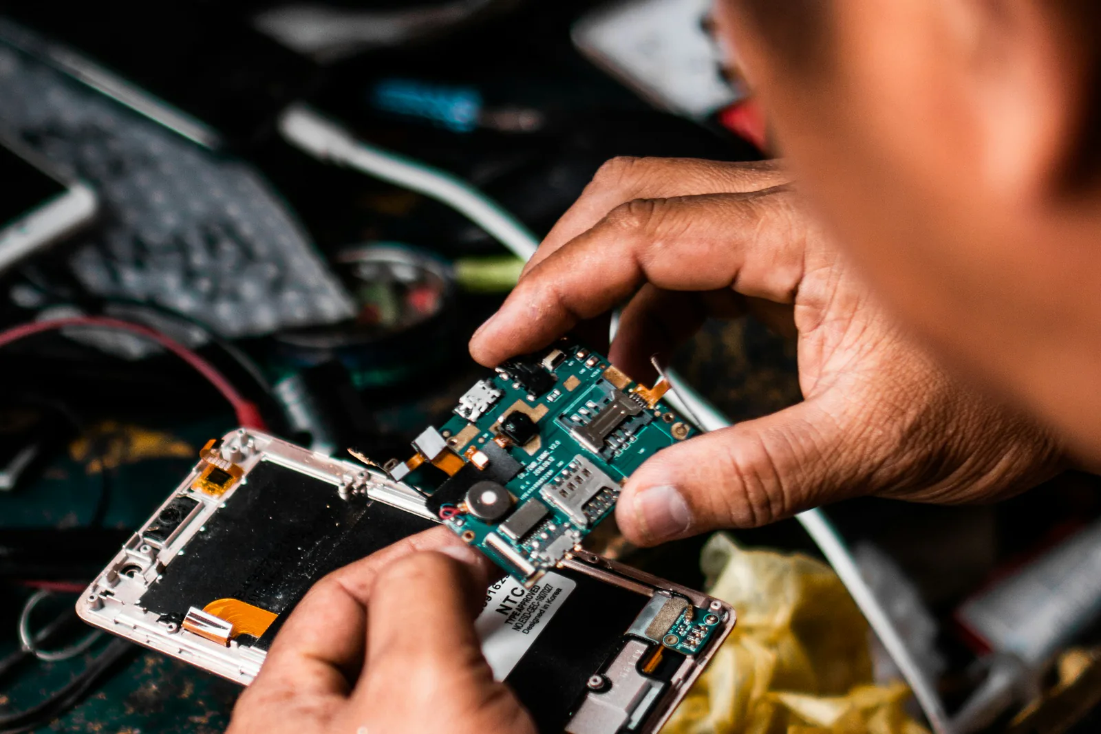 Hands repairing a smartphone circuit board