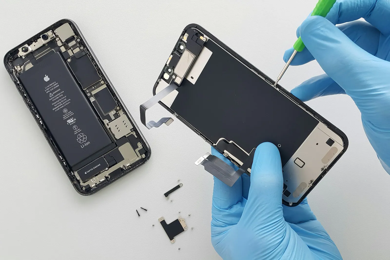 Technician in blue gloves replacing a phone screen