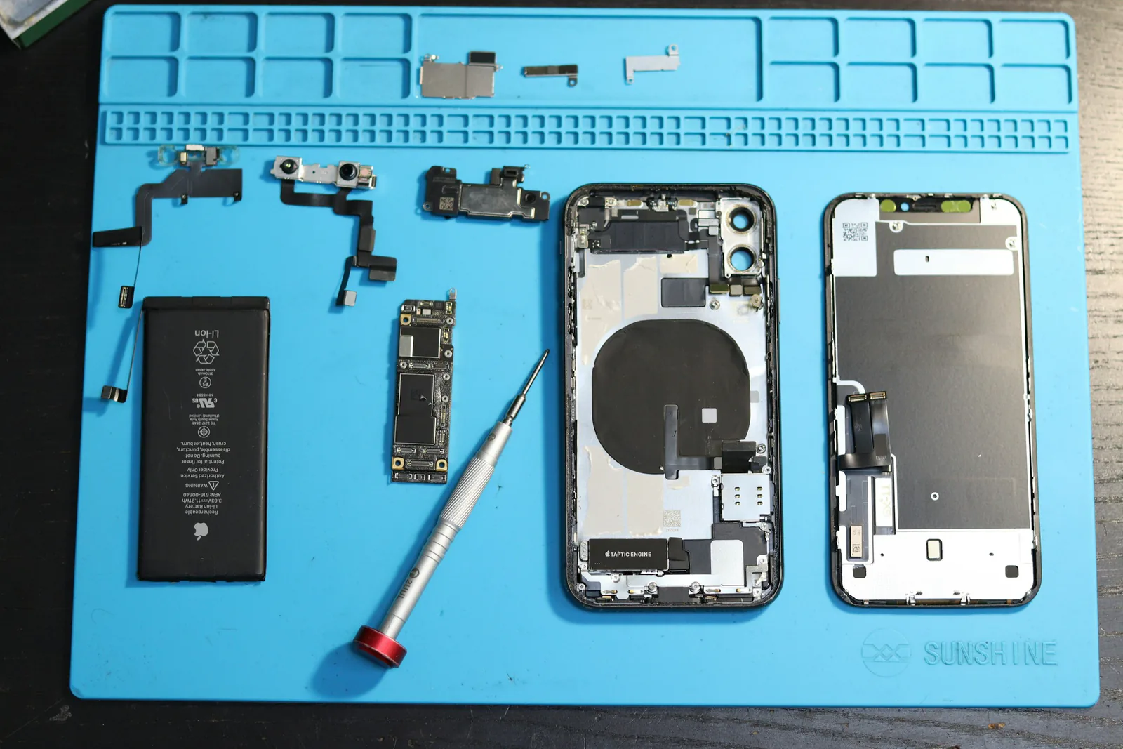 iPhone parts laid out on a blue repair mat