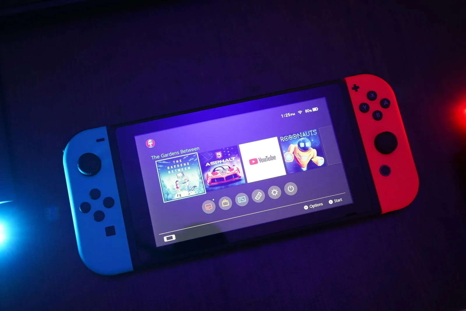 Handheld game console with its controllers attached, lit in blue